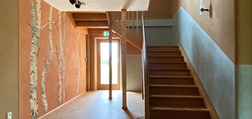 Flur mit großer Holztreppe und Wandgemälde im Strohtel. Das Wandgemälde ist Teil des Nachhaltigen Kunstkozepts des Gebäudes