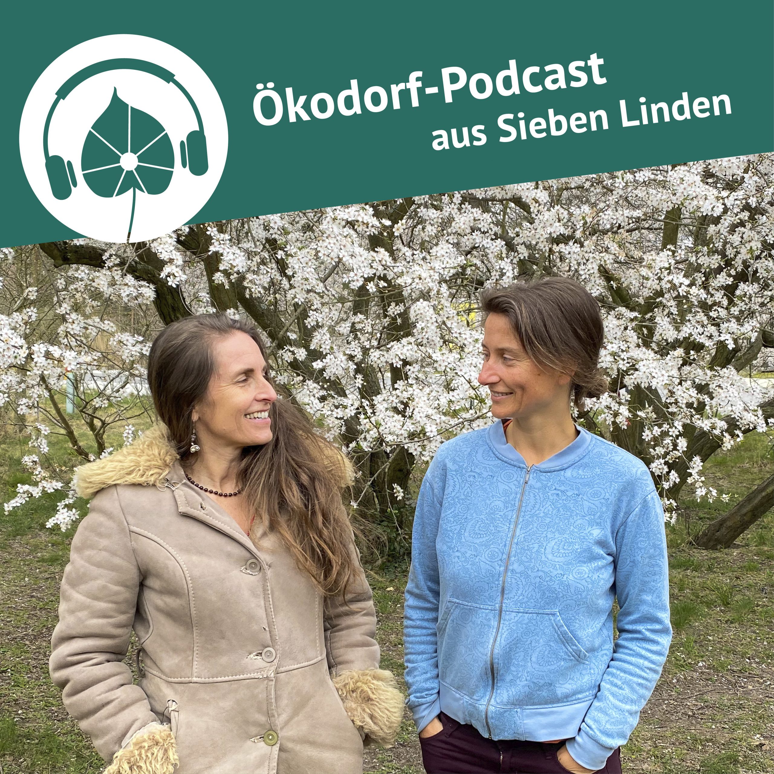 Simone und Alicia stehen vor einem blühenden Baum und lächseln sich an.