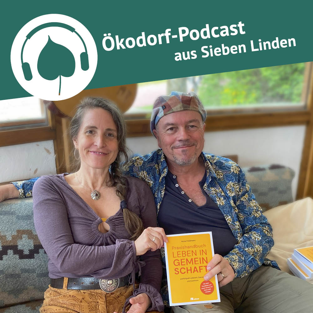 Simone und Heinz Feldmann sitzen auf einem Sofa und halten das Buch "Leben in Gemeinschaft" in die Kamera