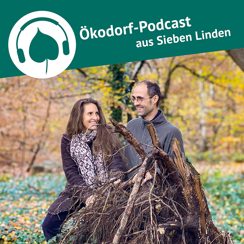 Julian und Simone sitzen vor einem Wurzelballen eines umgekippten Baumes