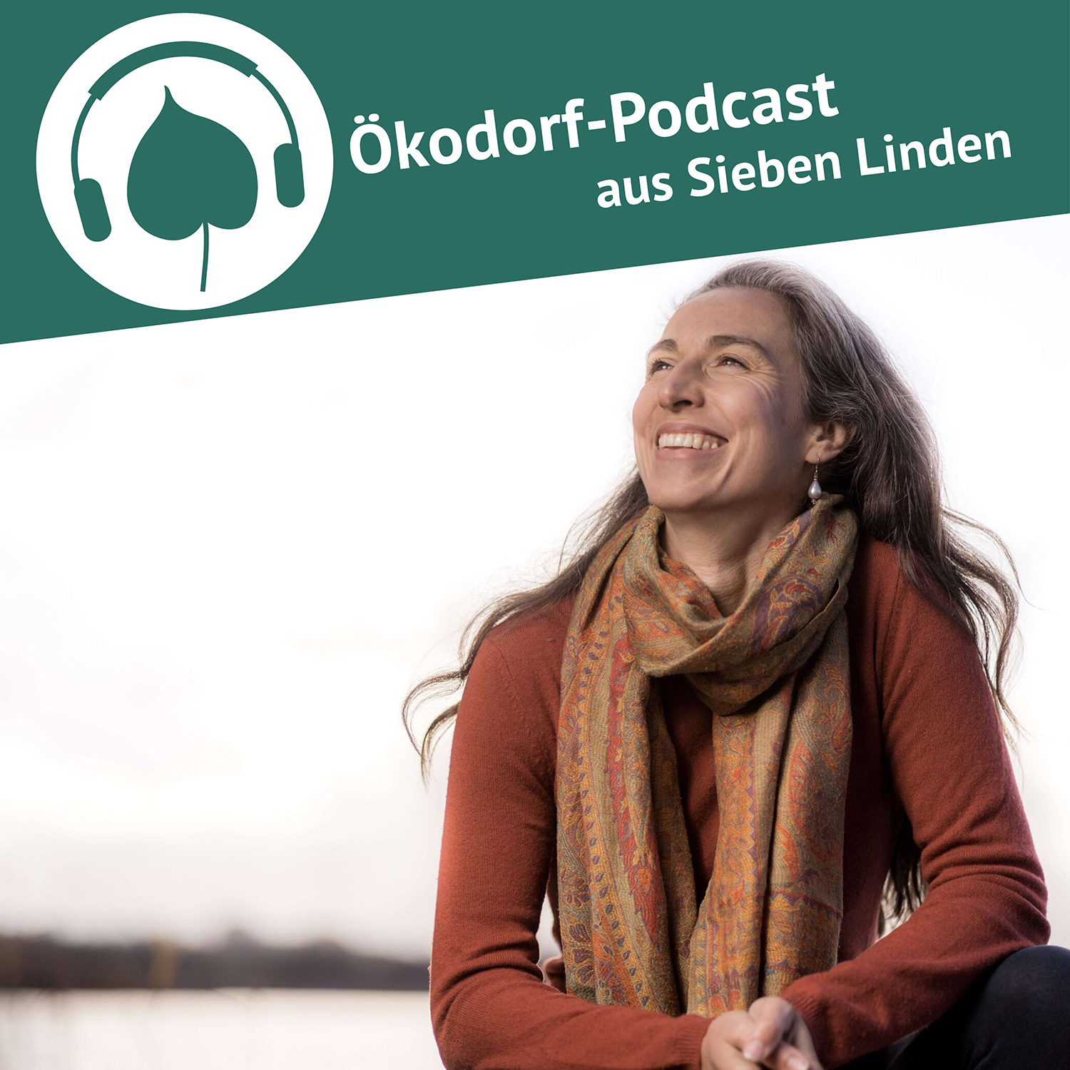 Vivian Dittmar schaut in den Himmel und hat ein breites lächeln im Gesicht. Sie trägt einen organgen Pullover und einen passenden Schal