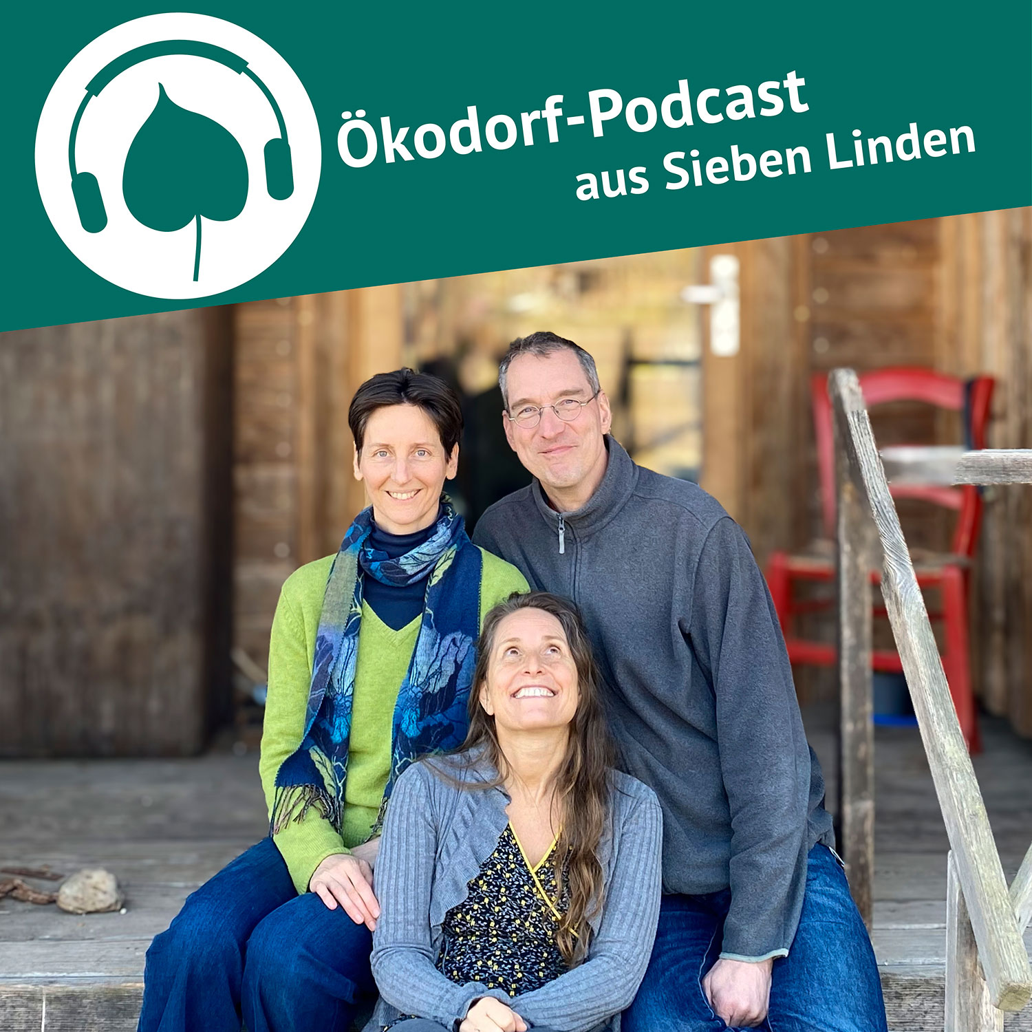 Eva. Stefan und Simone sitzen auf einer Holztreppe und schauen in die Kamera. Simone sitzt auf der Stufe vor dem Paar und schaut zu ihnen nach oben